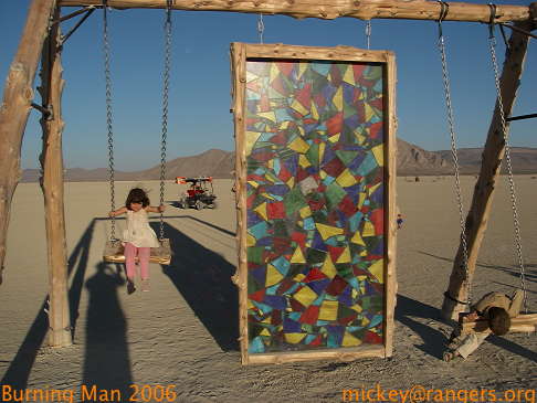 Burning Man 2006: Lila & Isaac on stained glass swing at dusk